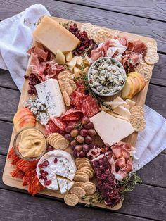 an assortment of cheeses, crackers and meats on a wooden platter