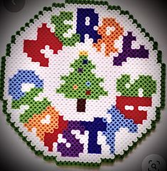 a cross - stitch christmas ornament on a white plate with green and red decorations