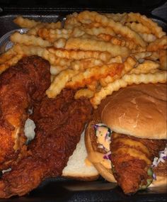 a tray filled with fried chicken, french fries and two burgers