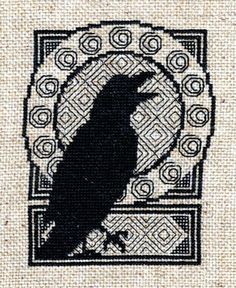 a black bird sitting on top of a piece of cloth with an intricate design in the background