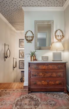 a room with a dresser, mirror and pictures on the wall above it is shown