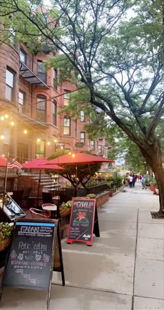 the sidewalk is lined with tables and umbrellas