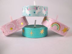 three candles with unicorns on them sitting next to each other in front of a white background