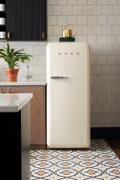 a white refrigerator in a kitchen next to a potted plant