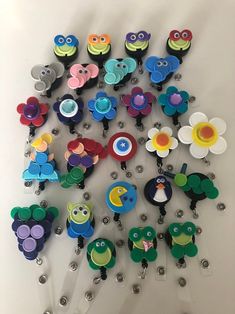 a bunch of different colored plastic objects on a white surface with eyes and flowers in the middle