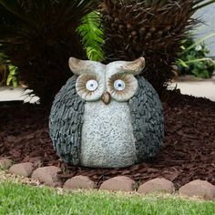 an owl statue sitting on top of a bed of mulch