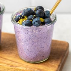 two cups filled with blueberries and oatmeal on top of a cutting board