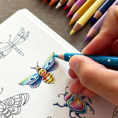 a person holding a pencil in their left hand and drawing with colored crayons