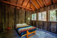 a bed in a room with wooden paneling and two windows on each side of it