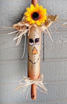 a scarecrow head with sunflowers on it hanging from the side of a building