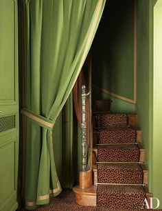 an open doorway with green curtains and leopard print rugs on the floor next to stairs