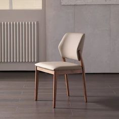 a white chair sitting in front of a radiator next to a wooden floor