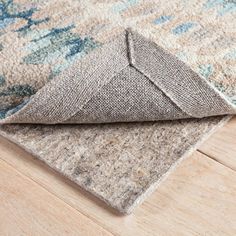 an area rug is laying on the floor with it's corner folded up to reveal a piece of fabric