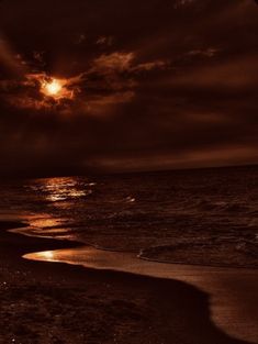 the sun is setting over the ocean with dark clouds