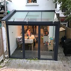 a person sitting at a table in a back yard with an extension to the patio