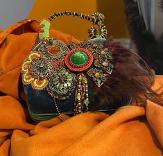 A piece of art on your arm! This Mary Frances bag has it all - velvet, beading, stone work, and feathers. You can carry it or display it, because it is just that beautiful! 7.5" wide x 8" tall x 3" deep Comes with dust bag. Mary Frances Black Green Orange Handbag, Bohemian Embellished Shoulder Bag For Gift, Bohemian Embellished Shoulder Bag As Gift, Mary Frances Bags, Mary Frances Handbags, Bowling Green Ky, Mary Frances, Top Handle Bags, Bowling Green