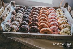 a box filled with lots of different flavored donuts on top of a table