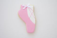 a decorated cookie with pink and white icing on it's side, next to a pair of shoes