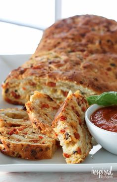 some bread and sauce on a white plate with a bowl of tomato sauce next to it