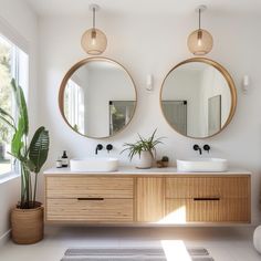 two round mirrors are above the double sinks in this bathroom