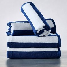 three towels stacked on top of each other in blue and white striped pattern, with one folded up to the side