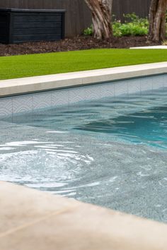 an empty swimming pool with green grass in the background