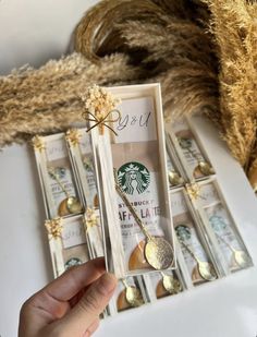 a person holding a starbucks cup and spoon in front of some fake gold leaf decorations