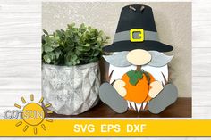 a gnome with a pumpkin sitting next to a potted plant on top of a table