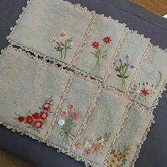 an embroidered piece of cloth with flowers on it sitting on top of a wooden table