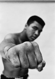 a black and white photo of a man pointing at the camera with his fist out