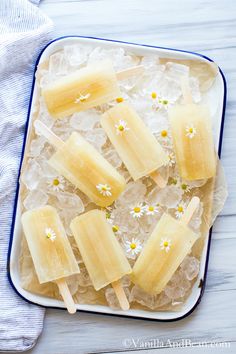 several popsicles are sitting on ice in a blue and white tray with daisies