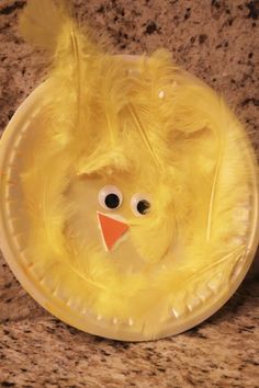 a yellow paper plate with a chicken face on it's side and eyes drawn on the front