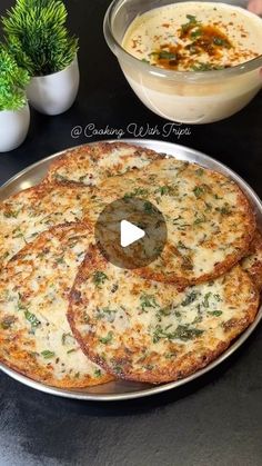 a pizza sitting on top of a metal pan next to a bowl of soup and potted plant