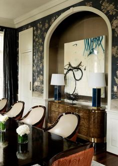 a dining room table with chairs and vases on it in front of a painting