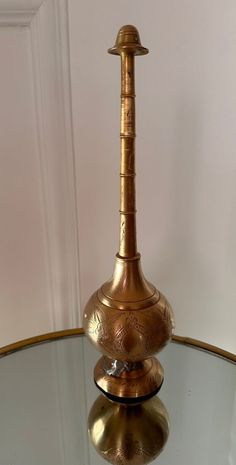 a golden vase sitting on top of a glass table