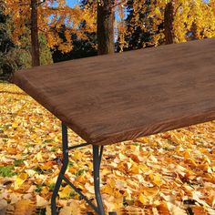 an ironing board sitting on top of a wooden table surrounded by yellow and orange leaves