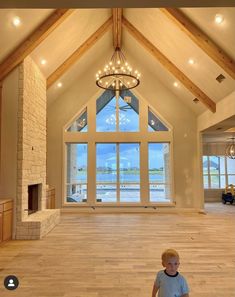 a young boy standing in the middle of a large room with wood floors and vaulted ceiling