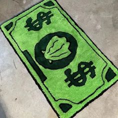 a green rug on the ground with dollar signs and leaves painted on it in black