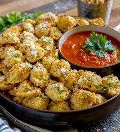 some food is in a black bowl on a table with sauce and parmesan cheese