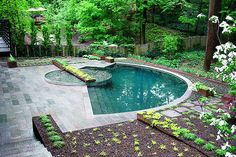 an outdoor pool surrounded by landscaping and trees