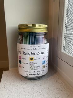 a jar filled with colored pencils sitting on top of a counter next to a window