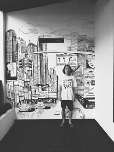 a young boy standing in front of a wall mural