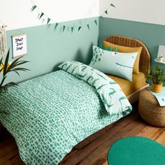 a bed room with a neatly made bed next to a green rug and potted plant