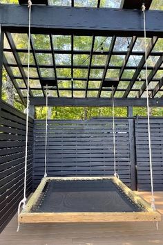 a swing bed in the middle of a wooden deck under a pergolated roof