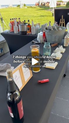 there is a table with wine bottles and other items on it at an outdoor event