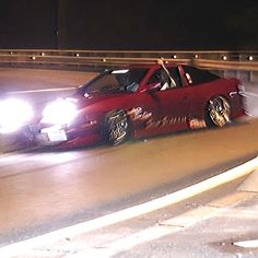 a red sports car driving down the road at night