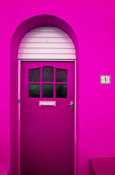 a bright pink door with arched window frames