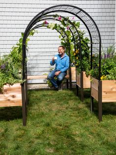 a man is sitting on a bench in the grass with plants growing out of it