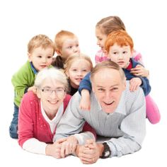 an older man laying on the ground surrounded by children and posing for a photo with his arms around him