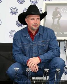 a man wearing a cowboy hat sitting in front of a sign with the words glaad on it